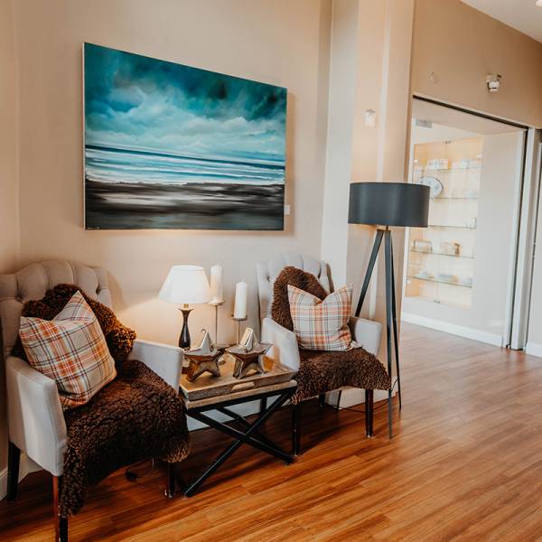 Eine Sitzgruppe mit gemütlicher Dekoration unter einem Gemälde eines Nordseestrandes in einem Hotel