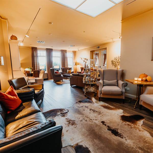 Ein großer Raum mit vielen gemütlichen Ohrensesseln und einem Kuhfellteppich auf dem Boden.