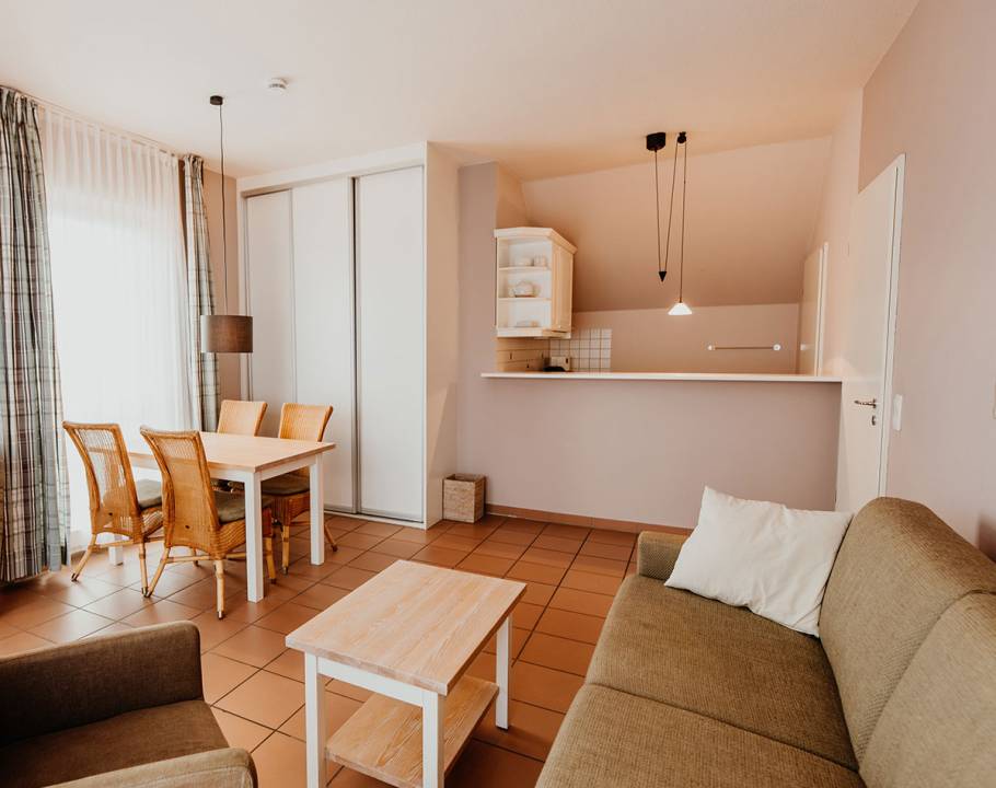 Eine voll ausgestattete offene Küche mit weißen Schränken und grauer Arbeitsplatte in einer Suite im Hotel Hüttmann.