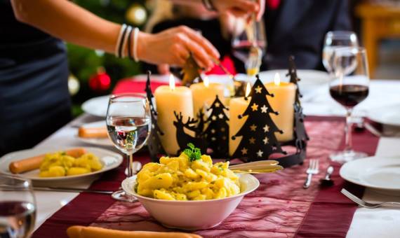 Klassisches Abendessen zu Heiligabend im Hotel Hüttmann mit Kerzen, Kartoffelsalat und festlich gedecktem Tisch im Hintergrund