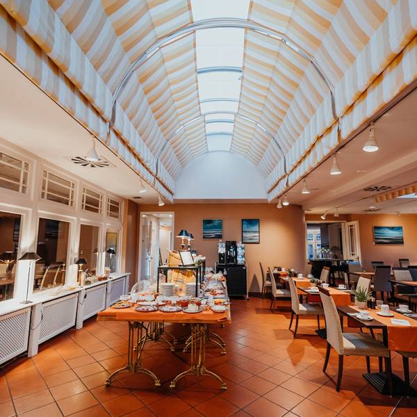 Der Frühstücksraum mit Buffet und gewölbter Decke mit Fenstern im Hotel Hüttmann.