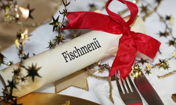 Weihnachtlich gedeckter Tisch mit Besteck und Menükarte für das Fischmenü am zweiten Feiertag
