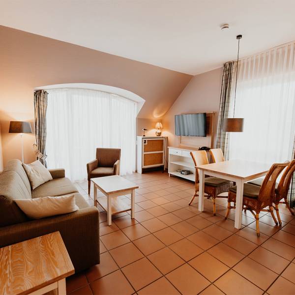 Der Wohnbereich mit Esstisch und Couch in einer Suite im Hotel Hüttmann auf Amrum.