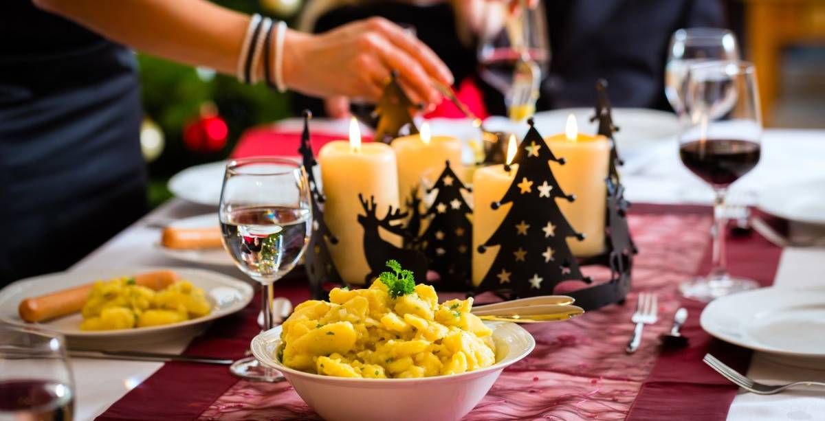 Klassisches Abendessen zu Heiligabend im Hotel Hüttmann mit Kerzen, Kartoffelsalat und festlich gedecktem Tisch im Hintergrund