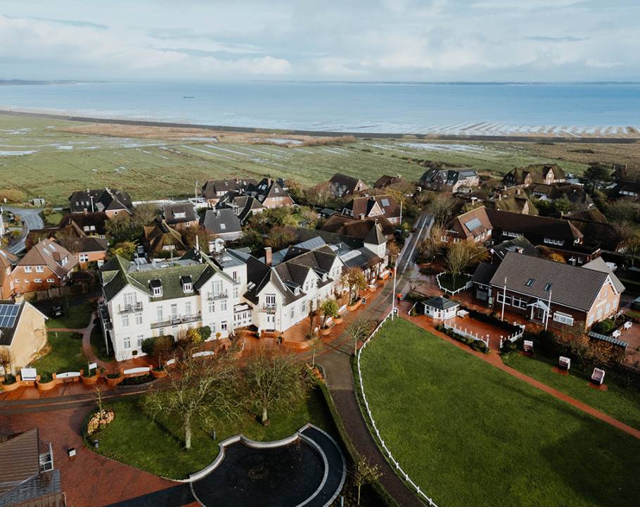 Luftaufnahme vom Hotel Hüttmann mit Ferienwohnungen in Norddorf. Im Hintergrund die Nordsee.