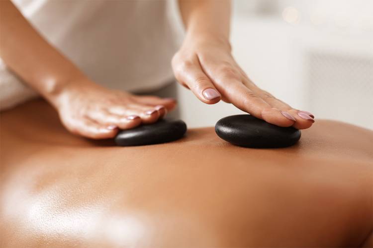 Nahaufnahme einer Hot Stone Massage als Teil der intensiven Behandlungen im Wellnessbereich des Hotel Hüttmann auf Amrum.