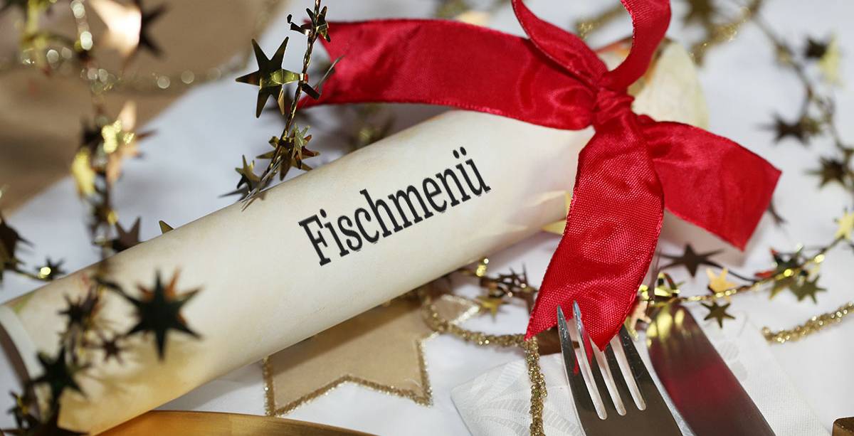 Weihnachtlich gedeckter Tisch mit Besteck und Menükarte für das Fischmenü am zweiten Feiertag