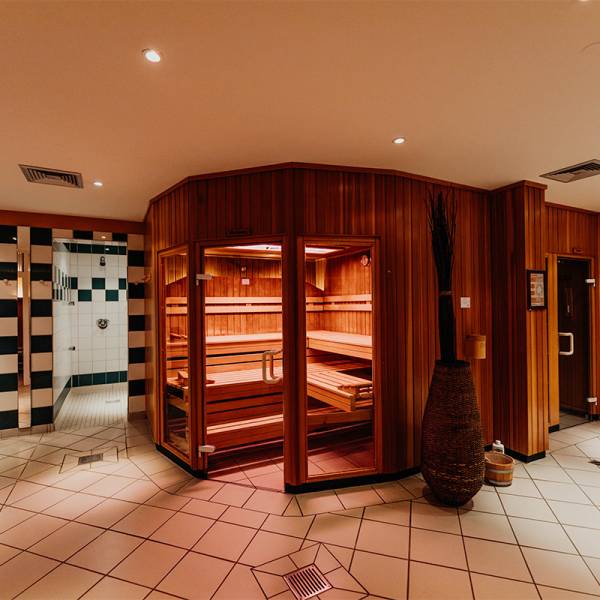 Eine Sauna aus Holz mit warmer Beleuchtung in einem Wellnessbereich.