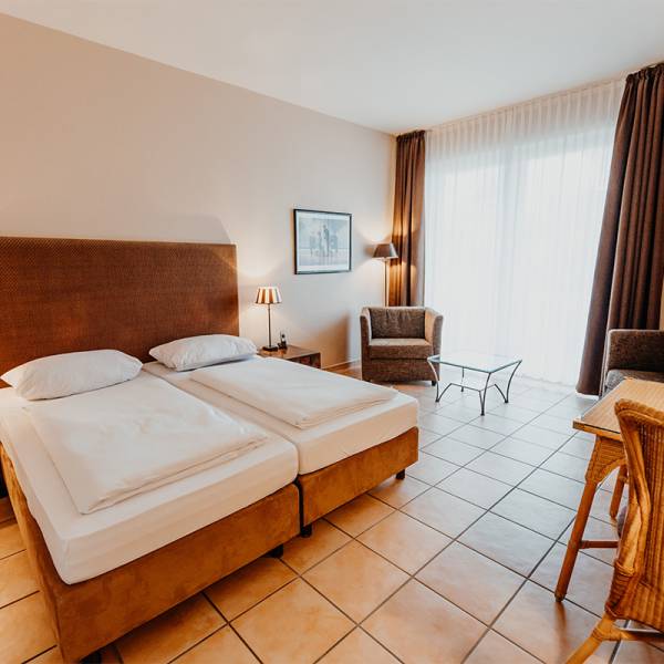 Ein Doppelzimmer mit gefliestem Boden eingerichtet mit braunen Akzenten im Hotel Hüttmann.