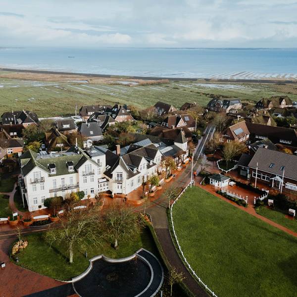 Luftaufnahme vom Hotel Hüttmann mit Ferienwohnungen in Norddorf. Im Hintergrund die Nordsee.