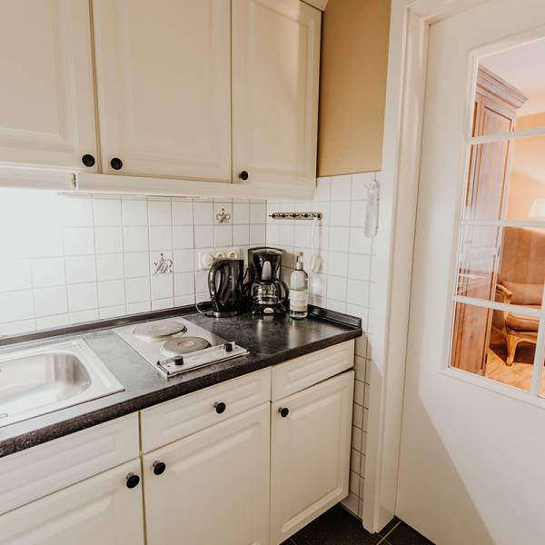 Eine Küchenzeile mit kleinem Kochfeld, Kaffeemaschine und Wasserkocher in einem Hotelzimmer.