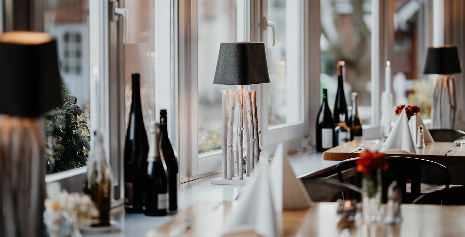 Geschmackvolle Tischdekoration mit Lampen und Weinflaschen im Hotel Hüttmann auf Amrum.