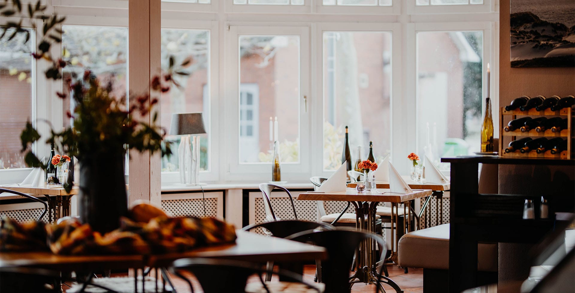 Elegant gedeckte Tische im Restaurant des Hotel Hüttmann auf Amrum mit Blick nach draußen.